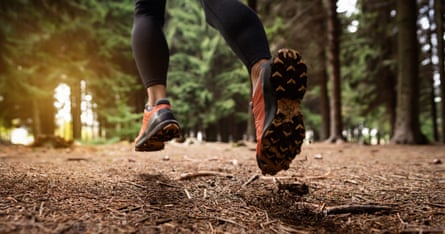 Rear-view of an unrecognisable female cross-country runner in winter sports running shoes, running in the forest