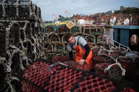 Deckhand Billy Ellis cleans lobster pots on a boat