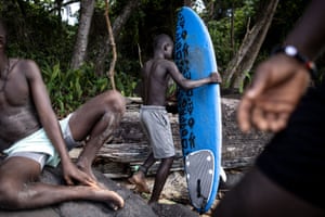 A young surfer carries his surfboard in Robertsport