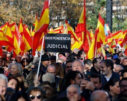 People wave Spanish flags and hold placards during a protest called by the People’s party in central Madrid
