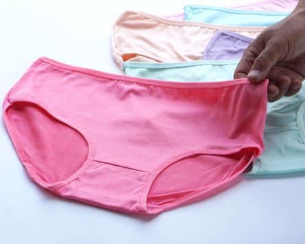 A hand holding a pair of colourful women's cotton pants.