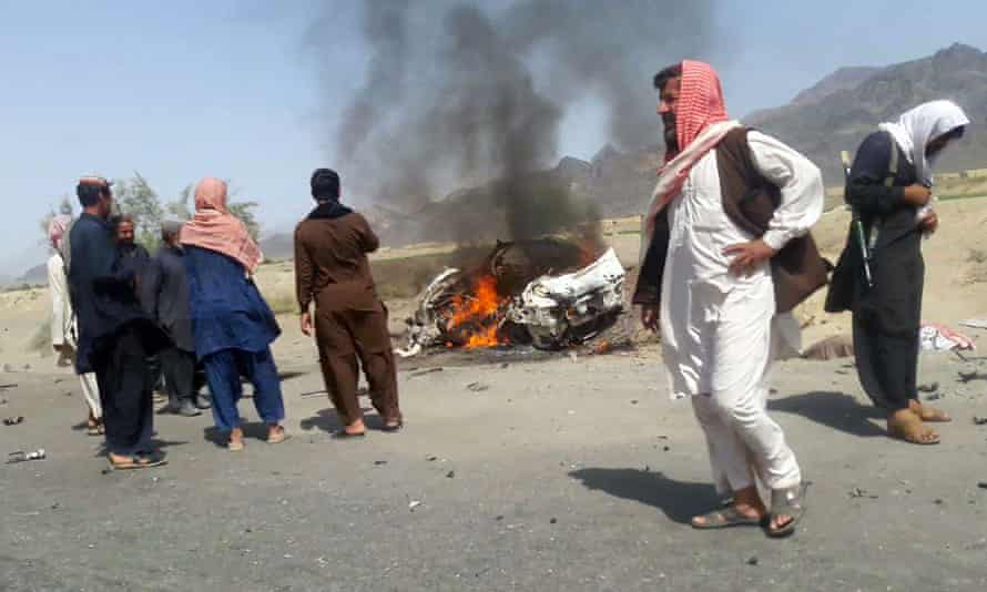 residents gather around a destroyed vehicle hit by a drone strike in which Mansoor was believed to be travelling.