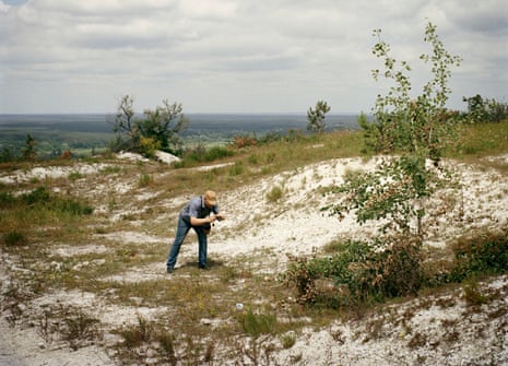 A man takes a photograph of the ground in an area of chalky grassland