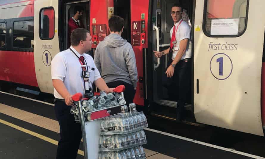 An LNER staff member provides bottled water for passengers stranded at Peterborough station.