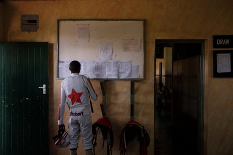 A jockey reads one of many papers on a board.