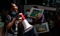 A teenage girl speaks into a megaphone in front of a crowd of people holding signs