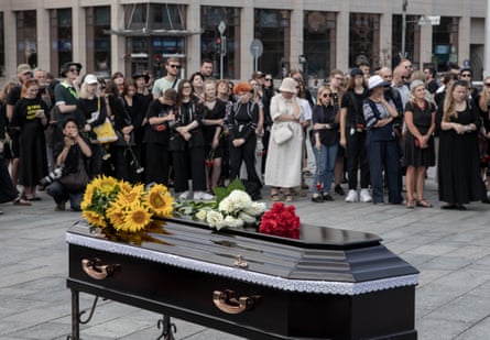 Mourners stand back from a coffin