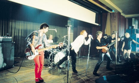 Sex Pistols on stage in London in 1976 with Vivienne Westwood, right, in background and Glen Matlock, left, in the red trousers.