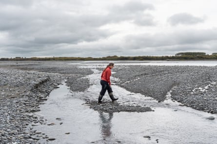 A woman walks across shallow water on a riverbank