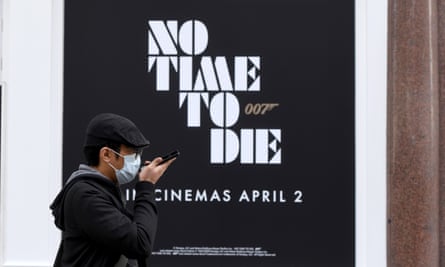 A man in London walks past a No Time To Die poster.