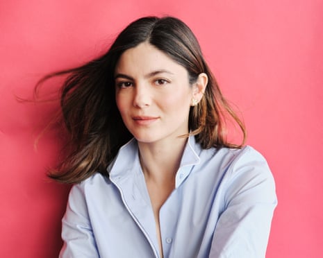 Actor Monica Barbaro in front of a light red backdrop