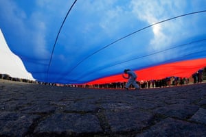 A girl runs under a giant Russian flag