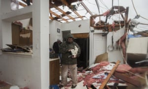 Bob Moore stands in his house in Rowlett, Texas, Sunday, Dec. 27, 2015, the morning after it was damaged by a tornado. At least 11 people died and dozens were injured in apparently strong tornadoes that swept through the Dallas area and caused substantial damage this weekend. (AP Photo/Rex C. Curry)