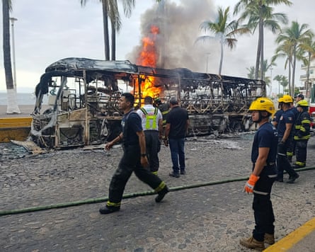 Firefighters work to extinguish a bus that was set on fire