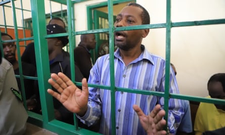 Man in striped shirt behind green bars