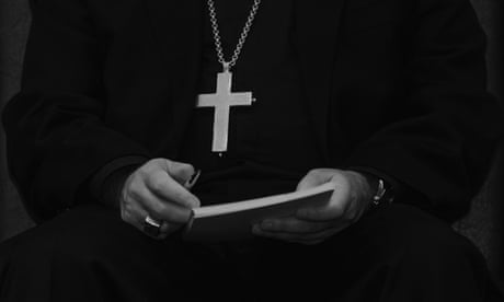 sacerdote con una cruz colgada en el pecho y sosteniendo un libro