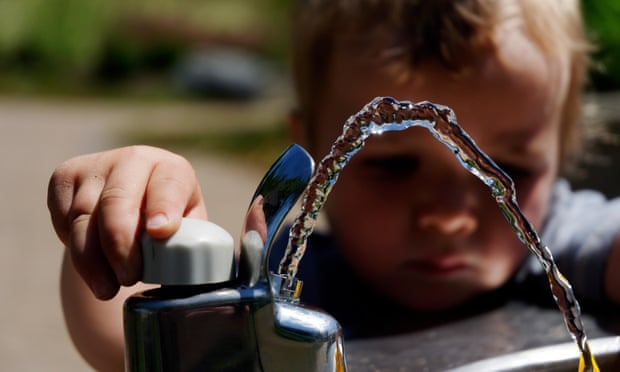 A young boy playing with a drinking water fountain