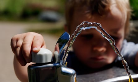 A young boy playing with a drinking water fountain.