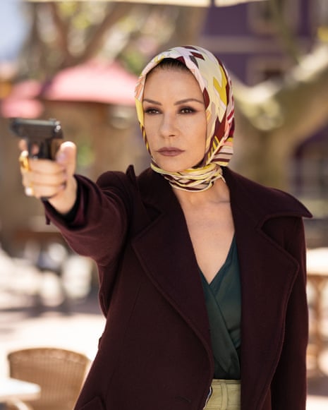 Catherine Zeta-Jones, as Jackie Price, points a handgun outdoors