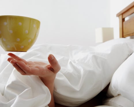 A woman being given a cup of coffee in bed