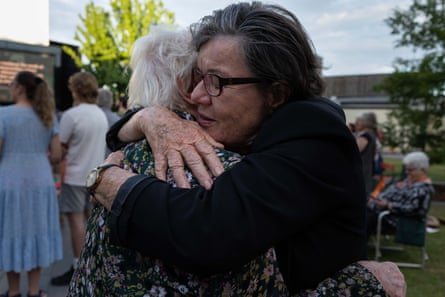 Cathy McGowan embraces a friend tightly at an outdoor community vigil