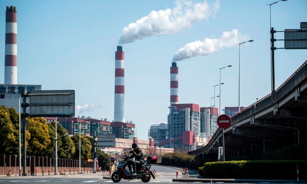 A man rides his scooter near the a coal power plant in Shanghai.
