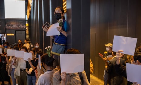 Mourners in Hong Kong hold blank sheets of paper during a vigil for the victims of the Ürümqi fire in China.