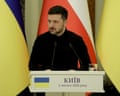 Volodymyr Zelenskyy stands at a lectern with Ukrainian and Polish flags behind him