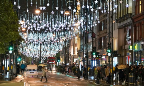 Christmas lights display illuminates Oxford Street in London as people walk along