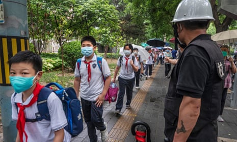 A security guard looks on as students arrive for classes as many schools reopened in Beijing