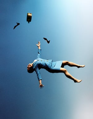 A woman in a blue suit with brass buttons falls from the sky, shoes and bag falling around her