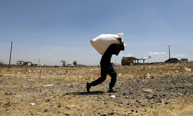 A man carries a sack of wheat flour from the Mona Relief charity at a camp for internally displaced people on the outskirts of Sanaa, Yemen, March 2021