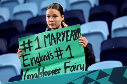 A teenage girl or young woman holds up a hand-painted sign reading “#1 Mary Earps England’s #1 goalstopper fairy”