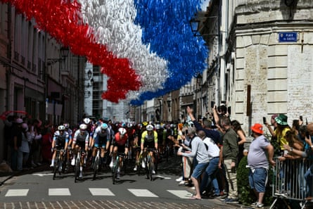 The peloton cycles under decorative streamers hung above the race route in Aire-sur-la-Lys.