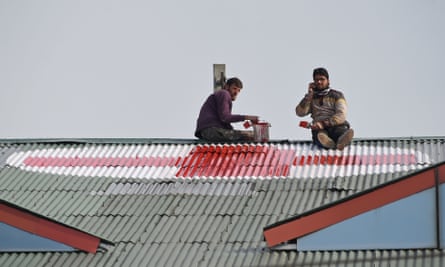 Workers paint a red cross on the rooftop of a hospital in Srinagar.