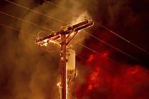 Fire burns along a power pole as the Sugar Fire tears through central Doyle