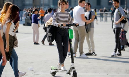 A woman rides an electric scooter from bike-sharing service company Lime through Paris.