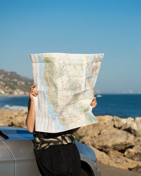 A person near the beach holding up a map