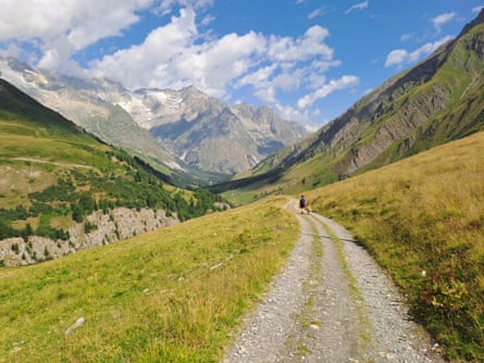A wide gravelly track in an Alpine valley