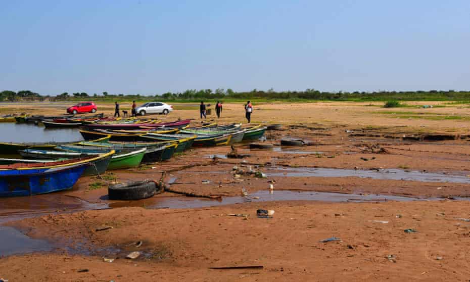 People walk next to boats along the exposed bed of a branch of the Paraguay river that has gone dry, in Lambare, Paraguay, on 17 September.