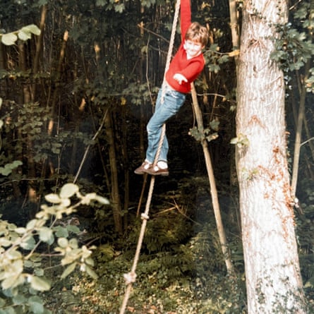 Young as a boy posing while climbing up a rope next to a tree.