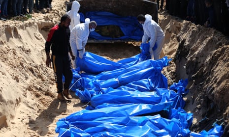 Palestinian workers bury bodies of those killed in Israeli attacks in a mass grave in the southern Gaza Strip city of Rafah on 7 March 2024.