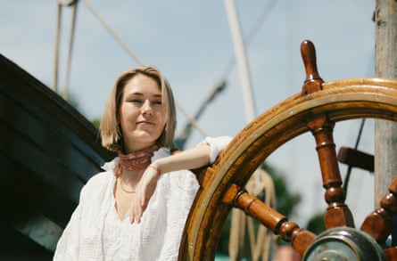 Woman in white shirt leans on the wheel of a Thames sailing barge