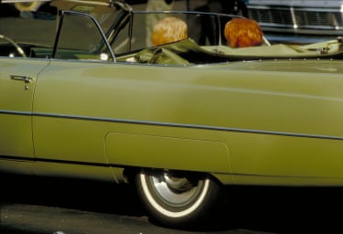 Two women with similar hair styles sitting in an old-fashioned green car