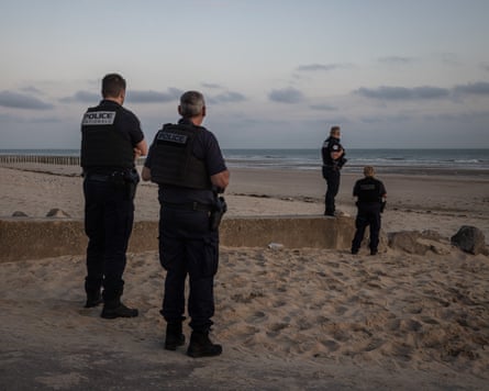 Four police officers on a sandy beach looking out to sea
