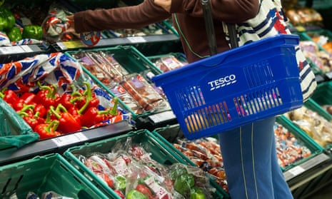 A customer browses the fruit and vegetable aisle in a Tesco Metro store.
