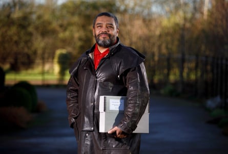 Al Nasir in leather coat outdoors holding folder