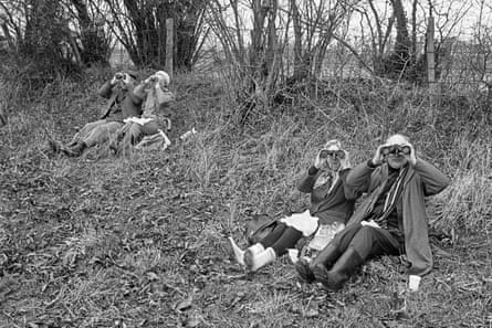 Black and white photograph from 1972 of two couples sitting on the ground birdwatching, binoculars held up to their eyes