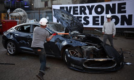 Two men, one with sledgehammer and one with a baseball bat, take swings at the car