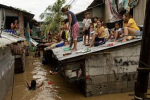 Residents wait on the roofs of their homes in San Miguel, Philippines for the flooding to subside after Super Typhoon Noru